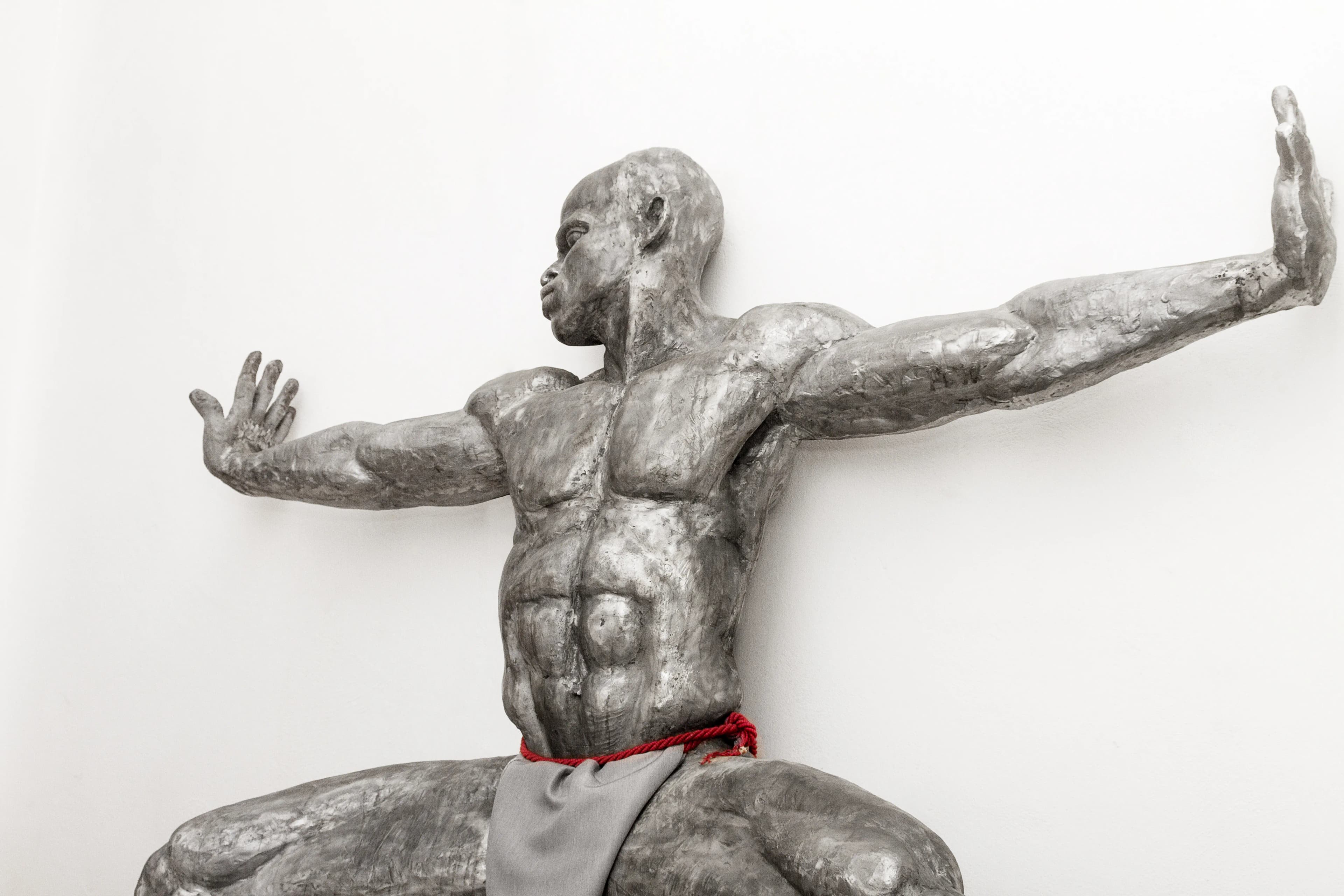 Infinity: a 218 cm tall aluminium sculpture of a Nigerian man crouching with hands outstretched