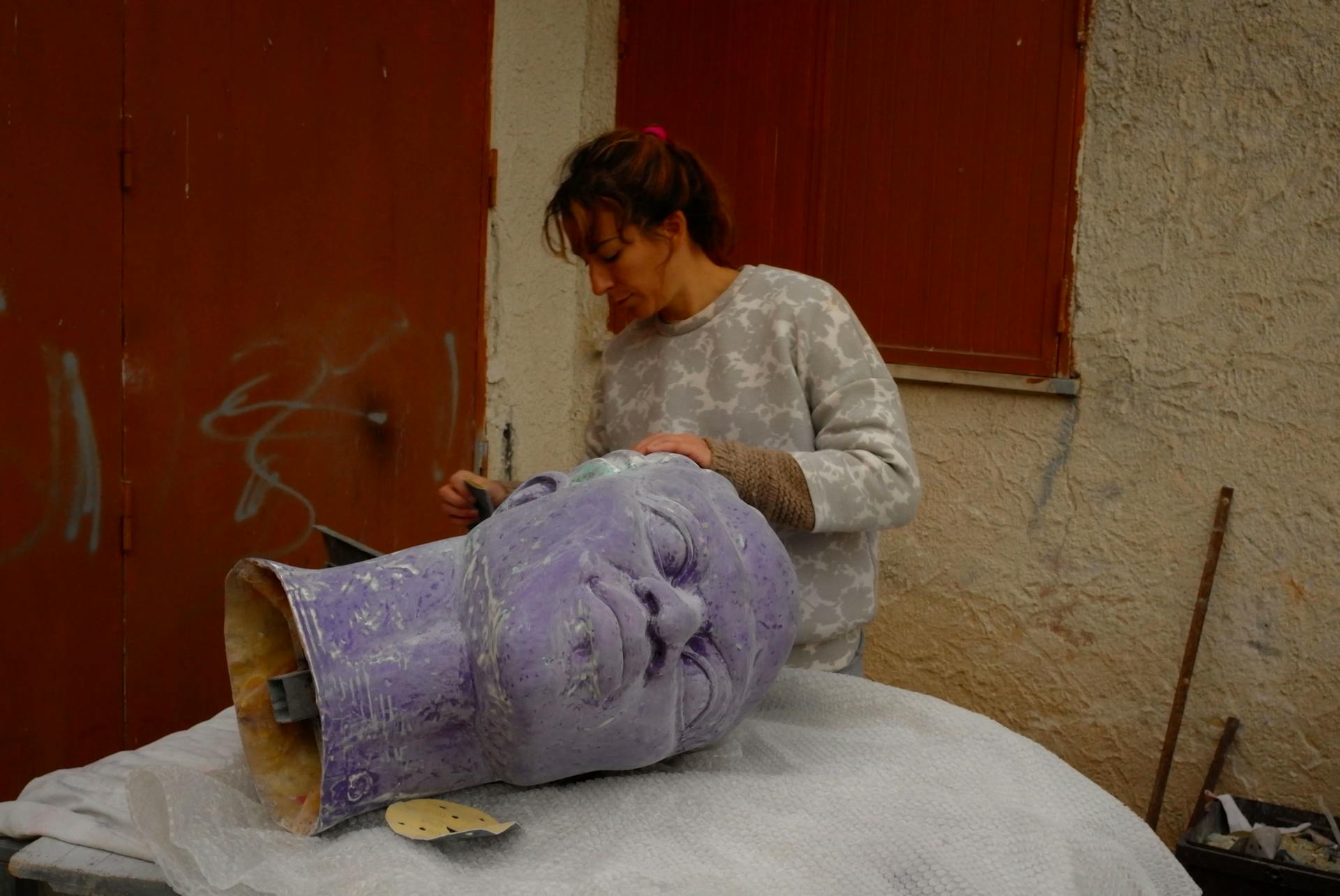 Gabriella shaping a large sculpture's head