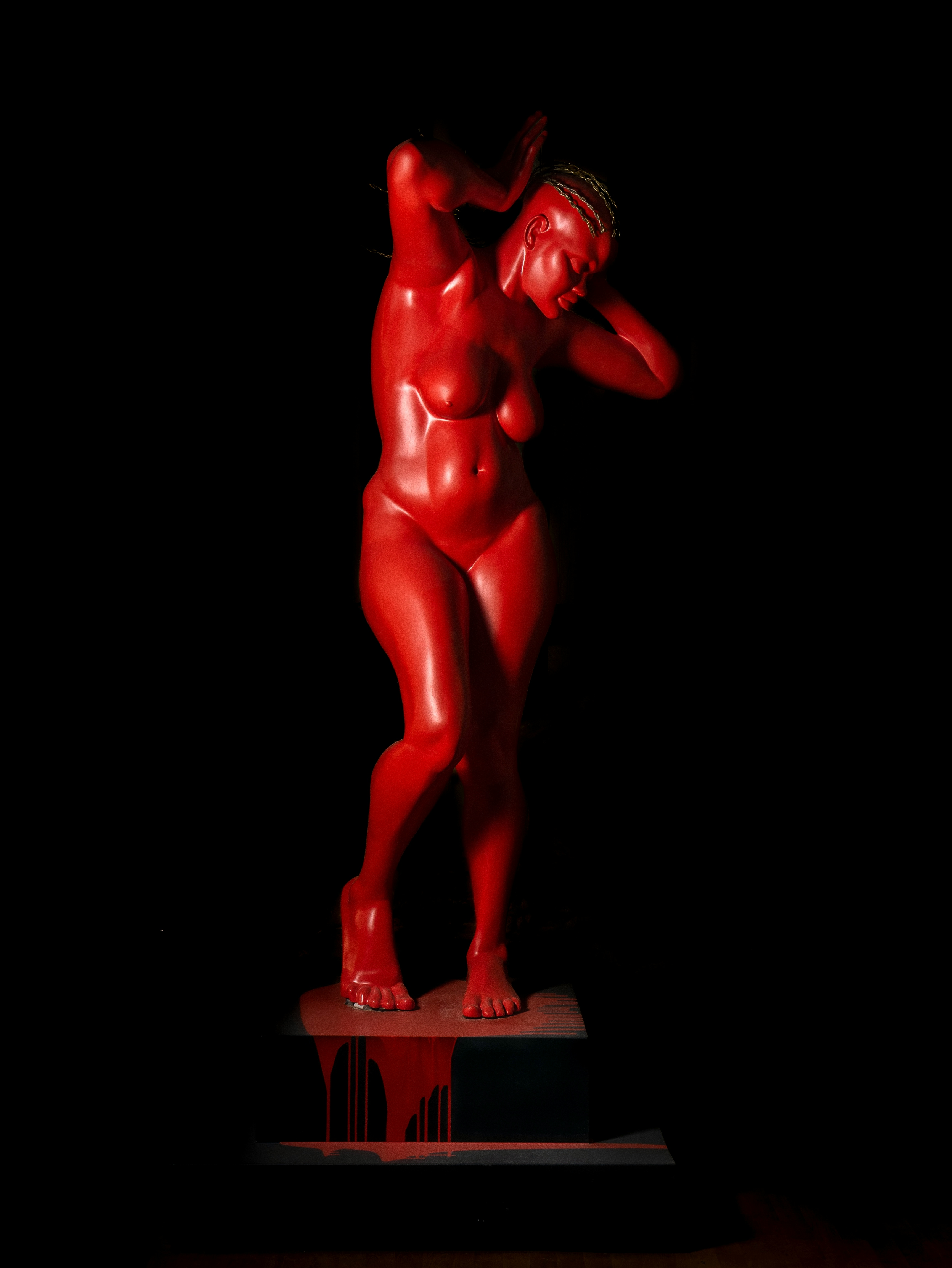 Pandora: a monumental, 210 cm sculpture on a pedestal of a beautiful Nigerian woman; cast in crimson coloured resin